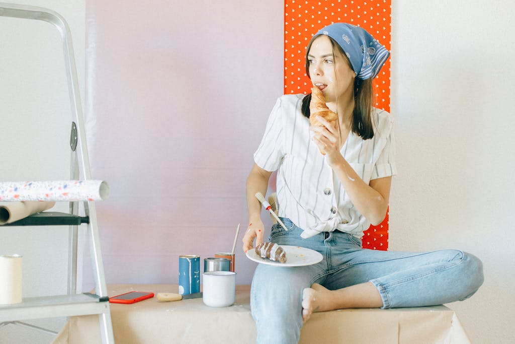 Young woman enjoying a croissant while taking a break from home renovation.